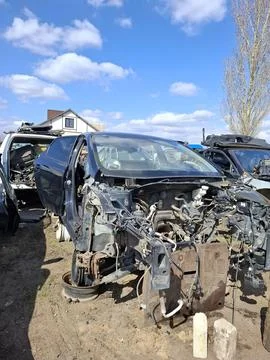 Stripped down car chassis with exposed engine parts in a salvage yard under.. Stock-Fotos