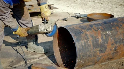 Stripping the pipe before welding, the worker cleans the surface Stock Footage 142495658