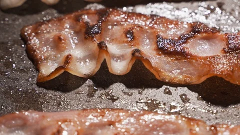 Strips of bacon are fried in a pan. Close-up, partial focus Video stock 122360909