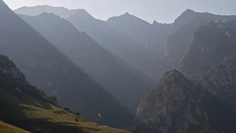 Strips of light rays in the mountains and a lone paraglider Stock Footage 85663842
