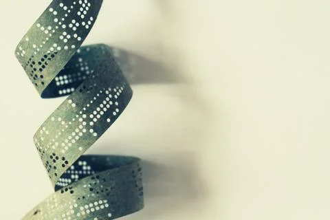 Strips of old punched tape on a white surface Foto stock