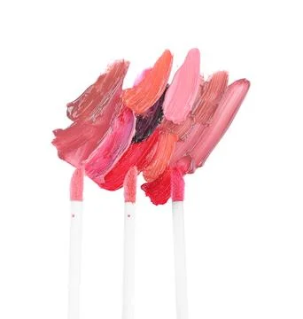 Strokes of different lip glosses and applicators isolated on white, top view Stock Photos