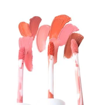 Strokes of different lip glosses and applicators isolated on white, top view Stock Photos