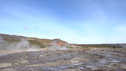 Strokkur geyser erupts while two tourists watch Stock Footage 112328772