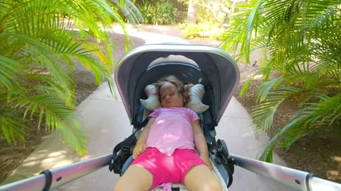 A stroller with a sleeping child being pushed down a garden path surrounded.. Stock Footage 286739037