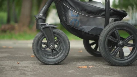 Stroller wheel closeup on pavement showing rubber tread suspension hub and rim Video stock 346392254