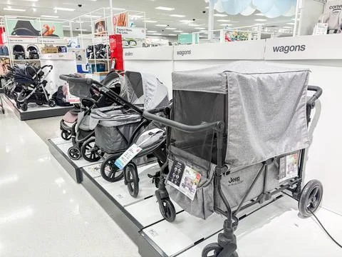 Strollers and stroller wagons displayed on a platform in a retail store - 0.. Stock Photos