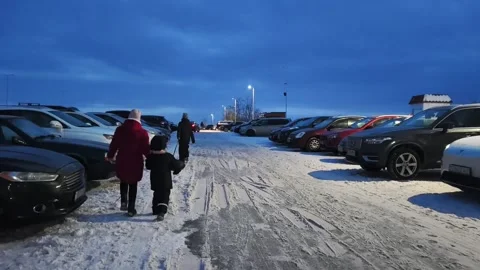 Strolling through a snowy parking lot at twilight with family members is a truly Stock Footage 345265824