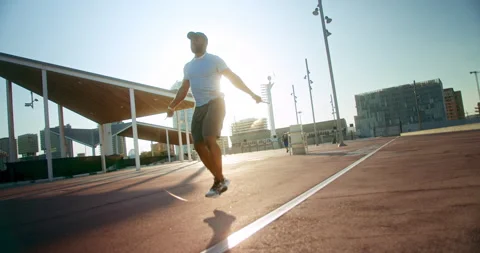 Strong active man jumping with rope exercising urban city landscape morning Stock Footage 140739712