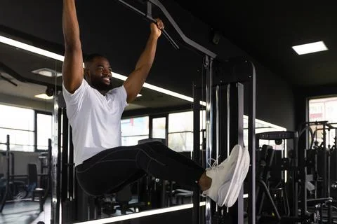 Strong african man doing statics exercise on horizontal bar, having workout a Stock Photos
