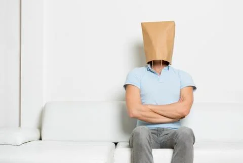 Strong anonymous man sitting on sofa with arms crossed. Stock Photos