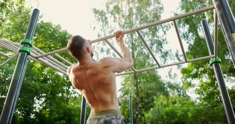 Strong athlete doing pull-up on horizontal bar.Young athletic man showing back Video stock 157207859