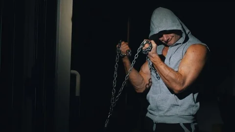 A strong athlete makes biceps exercises with a chain in a sports simulator. Stock Footage 88547931