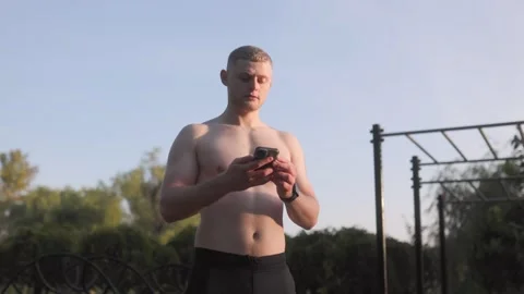Strong athletic guy using his smartphone at the gym, showing a fit physique. Stock Footage 287903772