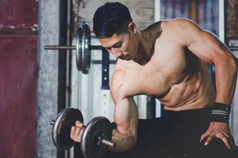 Strong athletic man Doing Exercises With Dumbbells in local gym Stock-Fotos