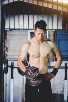 Strong athletic man Doing Exercises With Dumbbells in local gym Stockfoto's