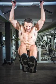 Strong athletic man on pull up bar and legs raised Stock Photos