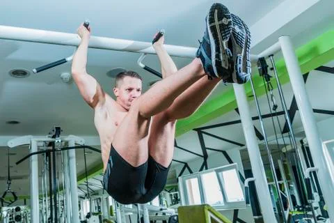 Strong athletic man on pull up bar and legs raised Stock Photos