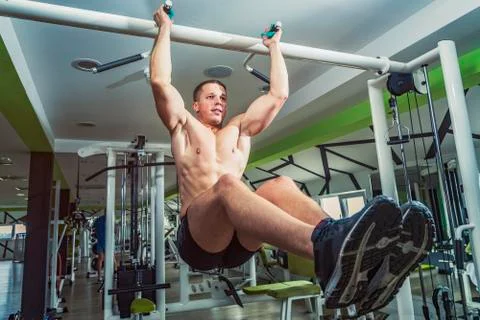 Strong athletic man on pull up bar and legs raised Stock Photos