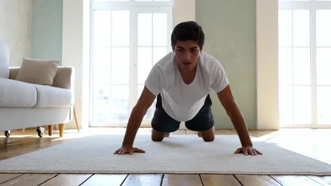 A strong athletic man in a white T-shirt and black shorts does crunchy exercises Stock Footage 131041871