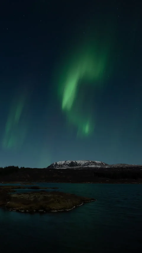 Strong aurora borealis over moonlit Thingvellir lake Iceland vertical format Stock Footage 326792699