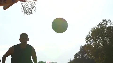 Strong basketball team men play outdoors street game sun silhouettes slow motion Stock Footage