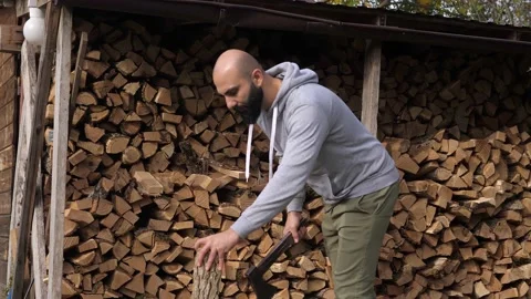 Strong bearded with a log and a sharp vintage axe preparing to chop wood for Stock Footage 220720480