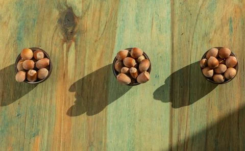 Strong beautiful in-shell hazelnuts in three ceramic small bowls on a light w 写真素材