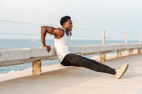 Strong black man doing exercise on parapet Foto stock
