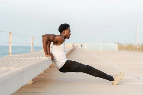 Strong black man doing exercise on parapet Foto stock