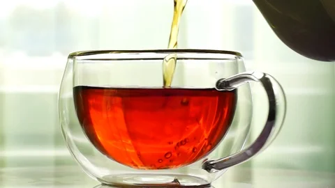 Strong black tea is poured from the kettle into rotating cup Stock Footage 116539698