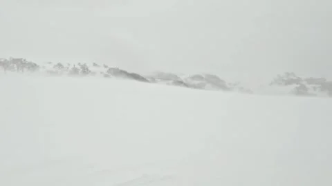 Strong blizzard wind blowing snow across a mountaintop winter landscape Stock Footage 272892228
