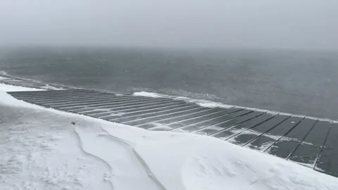 Strong blizzard wind blowing snow over sea waves during winter storm Stock Footage 319574220