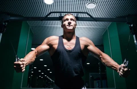 Strong bodybuilder doing chest exercise with cable ropes Stock Photos