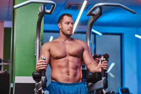 Strong bodybuilder doing excersise on a parallel bars in a modern fitness center Stock-Fotos
