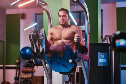 Strong bodybuilder doing excersise on a parallel bars in a modern fitness center Stock-Fotos