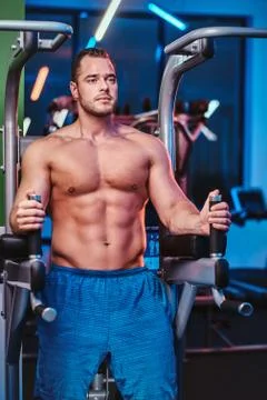 Strong bodybuilder doing excersise on a parallel bars in a modern fitness center Stock Photos