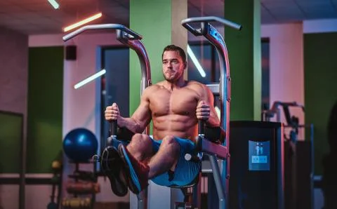 Strong bodybuilder doing excersise on a parallel bars in a modern fitness center Stock-Fotos