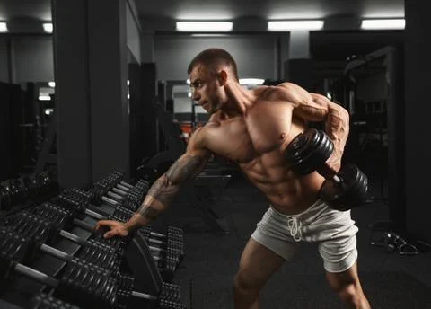 Strong bodybuilder doing exercise with dumbbell Stock Photos