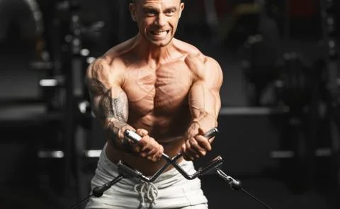 Strong bodybuilder doing exercise in the gym Stock Photos
