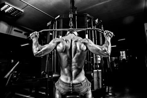 Strong Bodybuilder Doing Heavy Weight Exercise For Back On Machine Foto stock