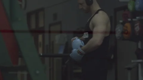 Strong bodybuilder man putting boxing gloves on, fighter training  Stock Footage 85657235