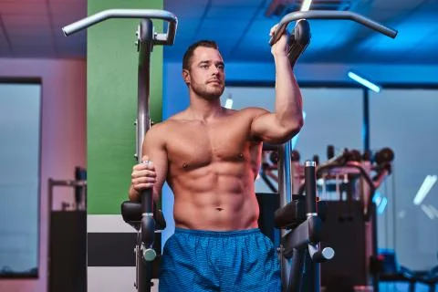 Strong bodybuilder standing on a parallel bars in a modern fitness center Stock Photos
