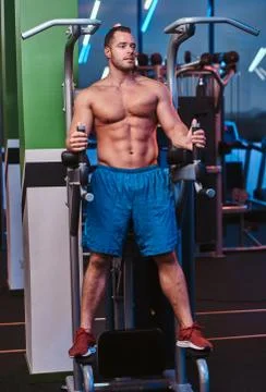 Strong bodybuilder standing on a parallel bars in a modern fitness center Stock Photos
