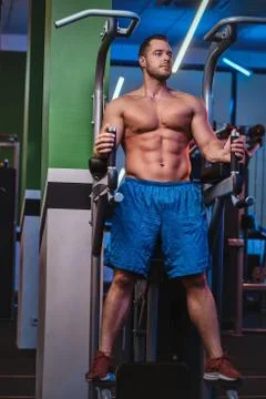 Strong bodybuilder standing on a parallel bars in a modern fitness center Stock Photos