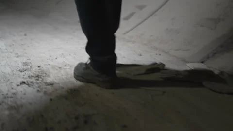 Strong boots step confidently across dusty tunnel floor Stock Footage 316098698