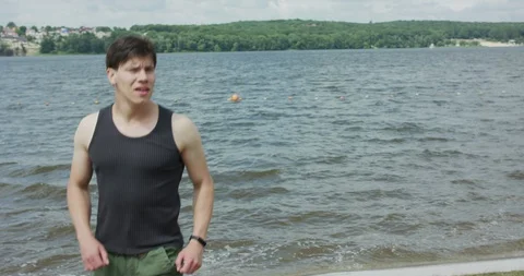 Strong boxer training kicks on open air at pond in a bright, windy day 動画素材 130129955