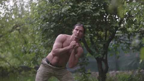 A strong-built Native American man flexes before training in the open air. The Video stock 133733966