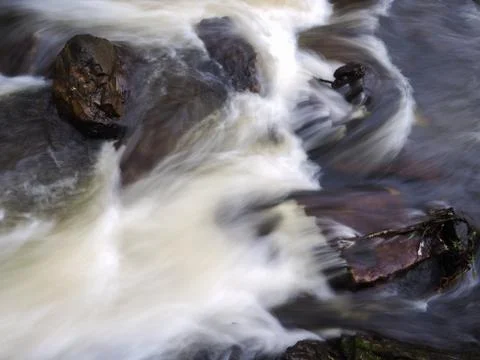 Strong current in river passing around rocks with long exposure Foto stock