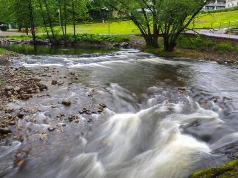 Strong current in river stream through a park Stock Photos